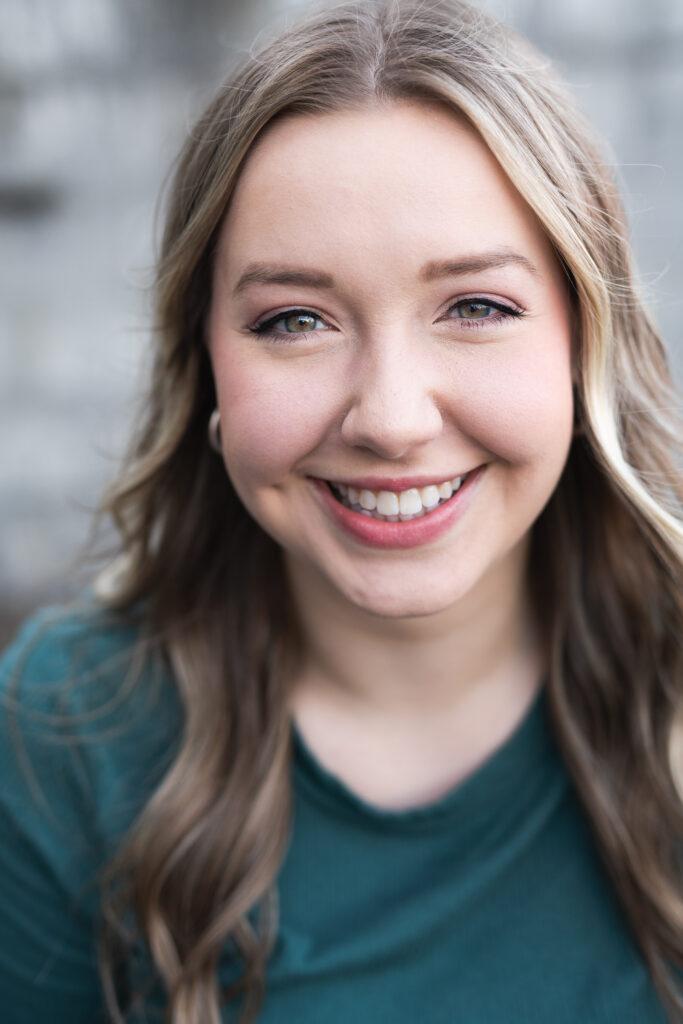 A headshot of Melanie Ernst smiling and wearing a green shirt | Actor, Director, Playwright, Stage Manager in Lynchburg, VA, Tampa FL